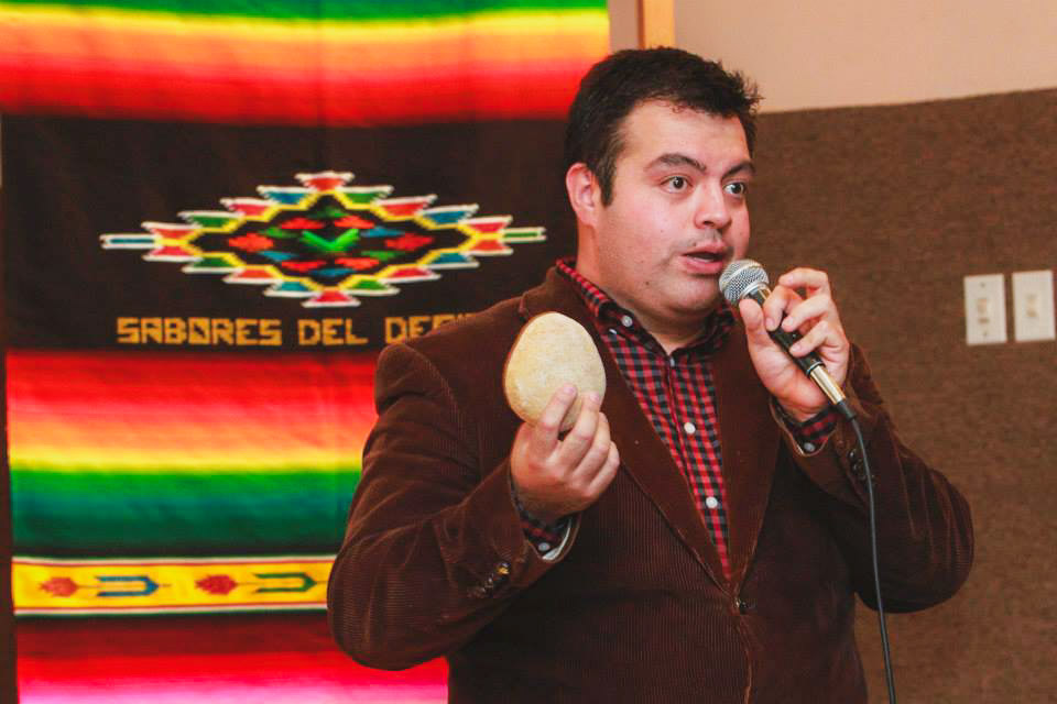 Hombre sosteniendo una pieza de pan con sarape de fondo