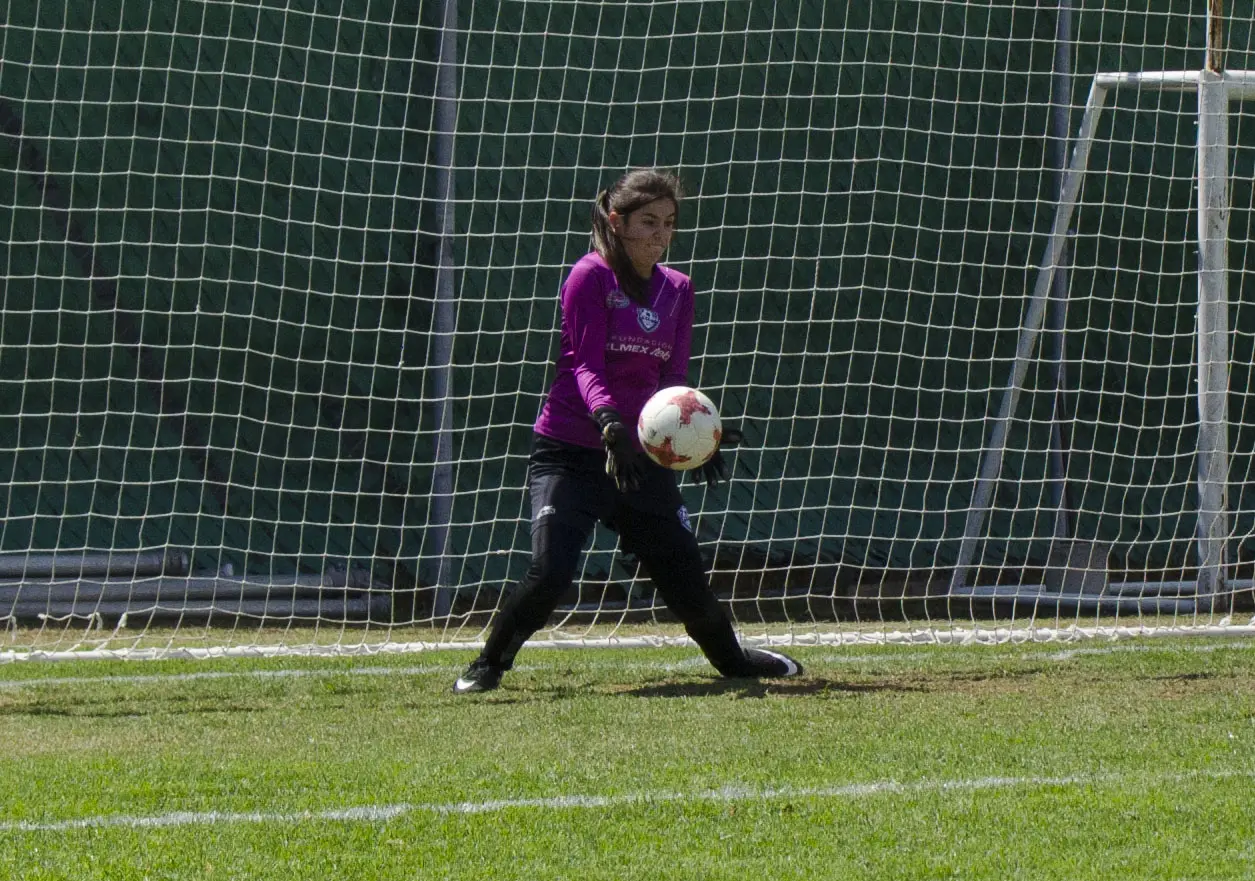 Jóvenes jugando fútbol en una cancha de pasto sintético