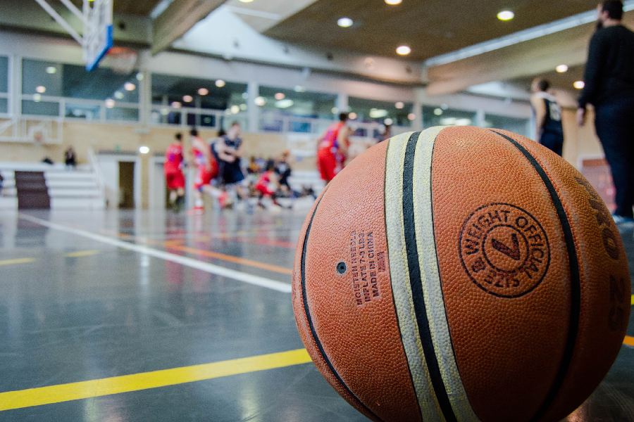 Balón de básquetbol al frente. Equipo en la parte de atrás.