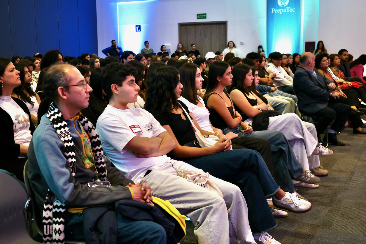 Auditorio lleno de estudiantes de PrepaTec sentados y atentos durante una conferencia del Encuentro Nacional de L&iacute;deres con Sentido Humano. La imagen muestra filas de j&oacute;venes escuchando una charla en un espacio iluminado, como parte de las actividades formativas del evento.