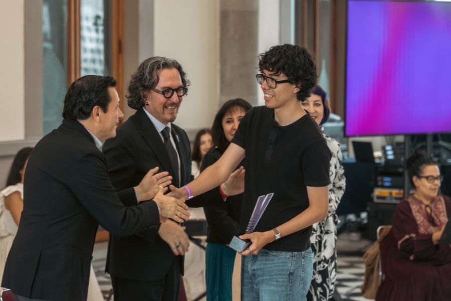 Estudiante recibe un reconocimiento de manos de organizadores durante la ceremonia del Concurso de Creaci&oacute;n Literaria de VIBRART 2026.