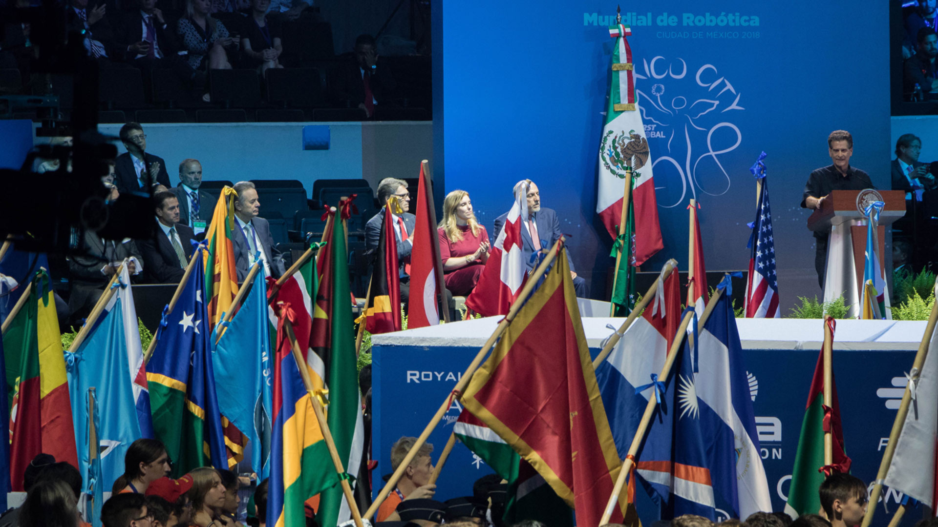 Dean Kamen frente a grupo de personas con banderas del mundo