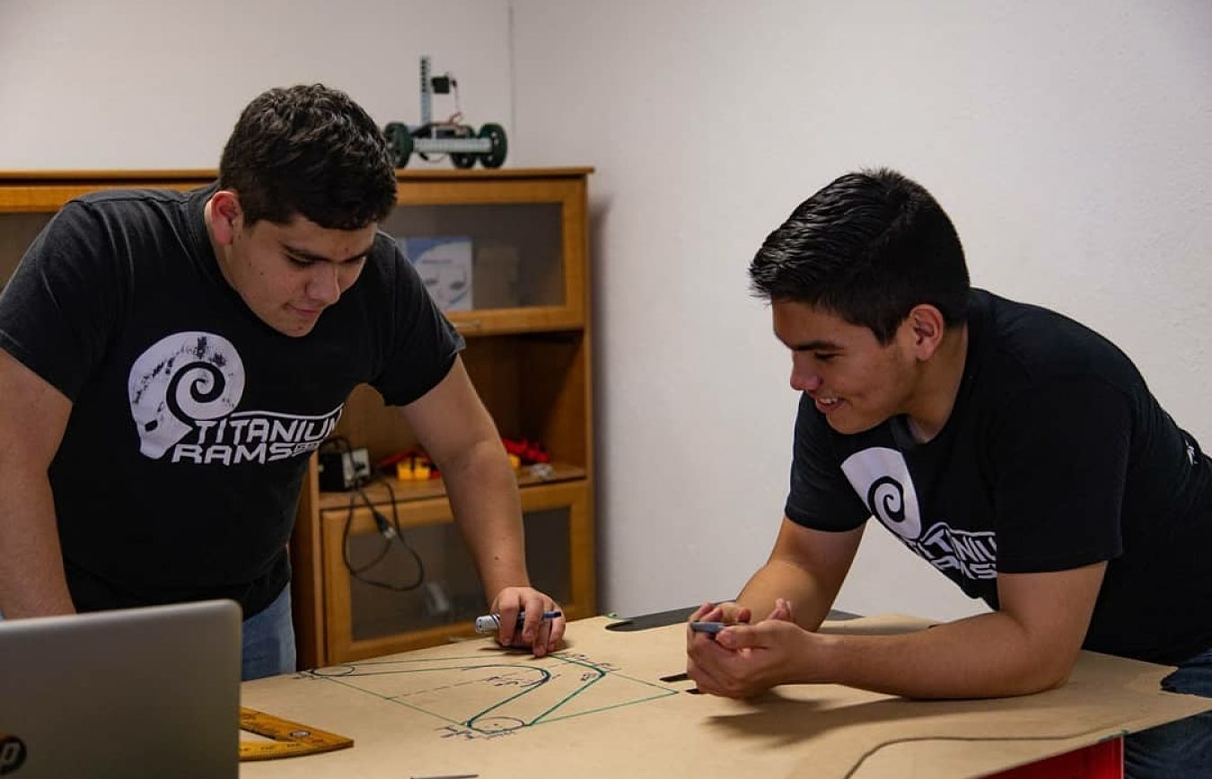 Alan trabajando colectivamente en un robot con su compañero