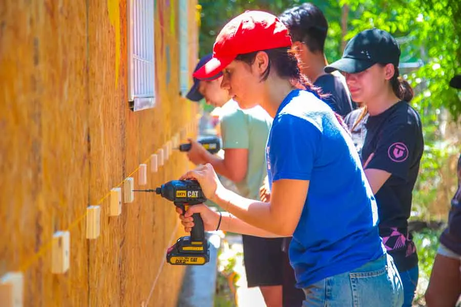 Alumna del Tec sostiene un taladro y trabaja en construcci&oacute;n de aula.