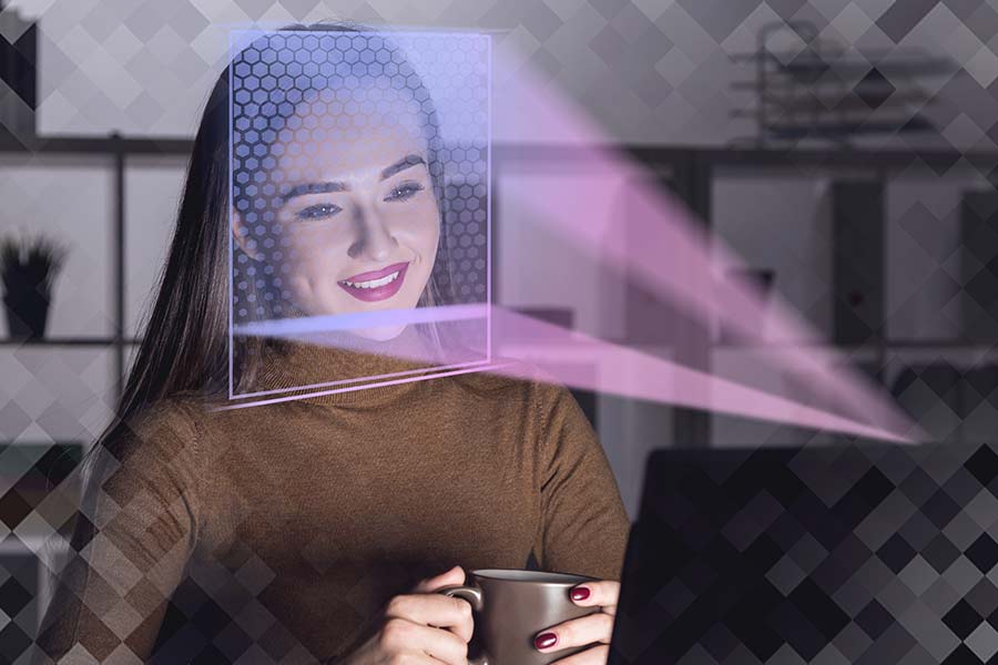 Joven mujer frente a una laptop que utiliza tecnología de reconocimiento facial.