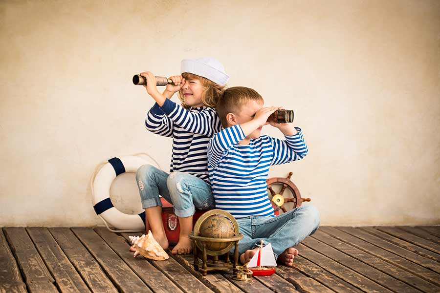 Niños jugando en casa simulando navegar un barco