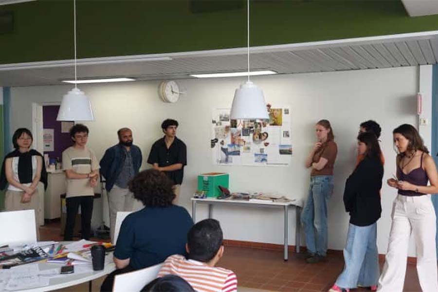 Grupo de 8 arquitectos presentando un proyecto frente a un salónd de clases.