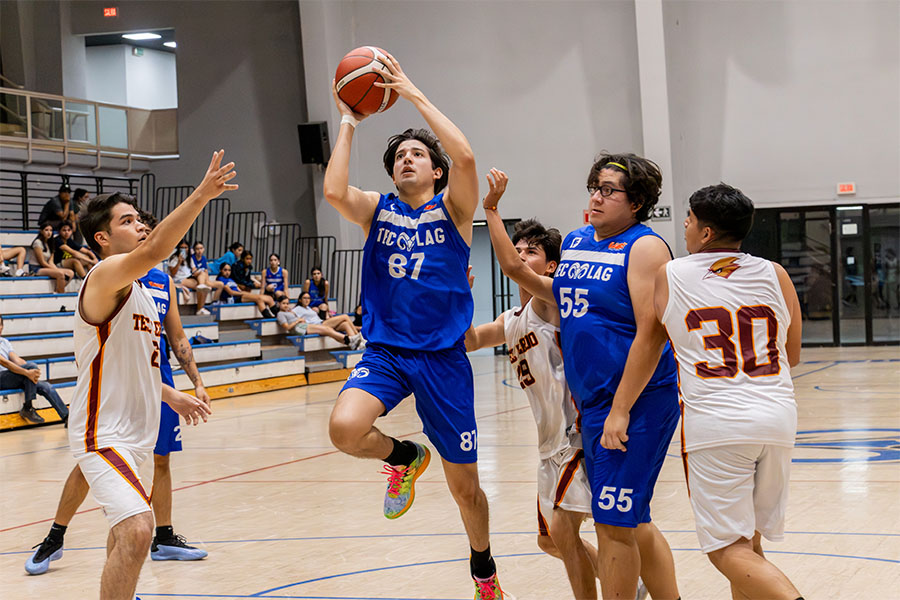 Jugadr de Brregos Laguna luciendo uniforme negro se enfila a encestar ante la marca de un rival con uniforme blanco