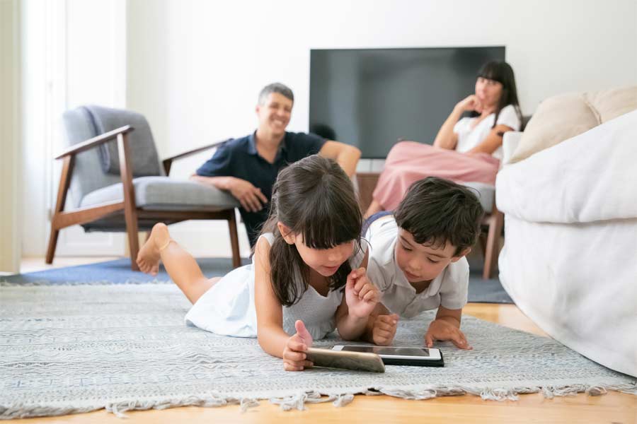 Padres cuidando hijos mientras usan tablets