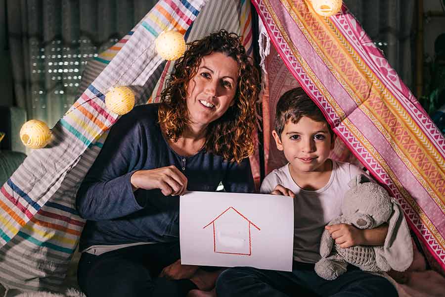 Mamá e hijo en una tienda de campaña hecha con sábanas dentro de casa