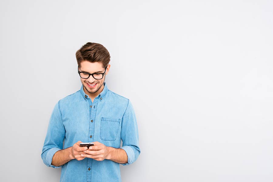 Joven sonriendo viendo su celular