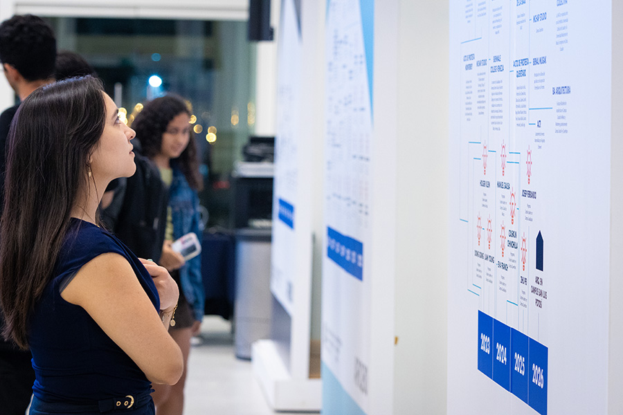 mujer estudiante frente a linea del tiempo de la carrera de arquitectura
