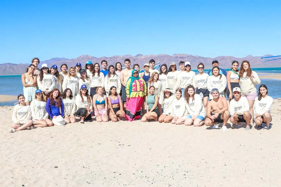 Foto grupal de jóvenes del Tec con representante de la comunidad Comca'ac en la playa.
