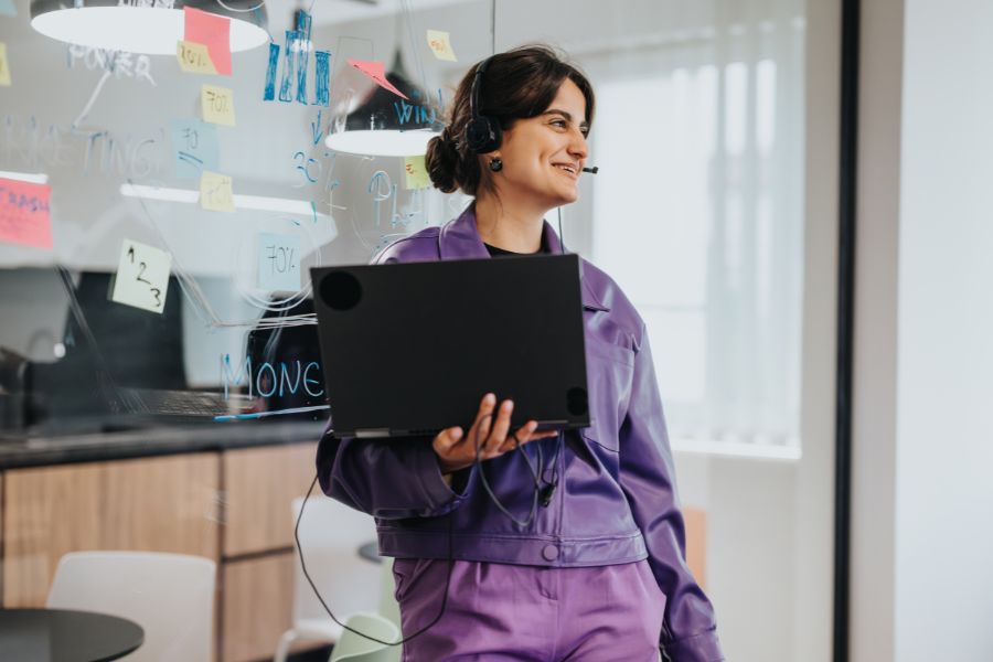 Mujer joven en oficina, con su laptop, sonriendo