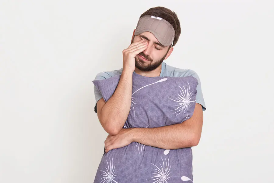 hombre somnoliento con una cobija y almohada