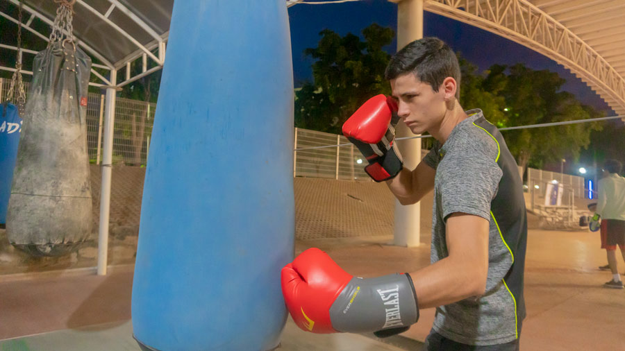 Joven deportista pegándole al costal durante entrenamiento de box