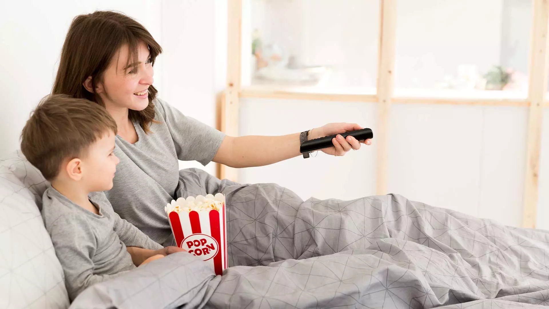 Mamá e hijo viendo una película desde su cama