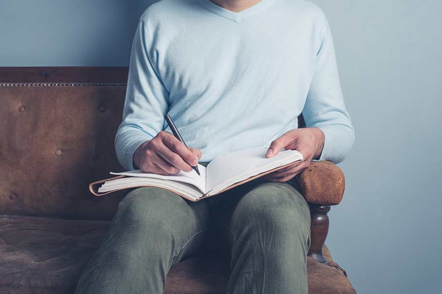 Manos de un chico joven escribiendo un diario