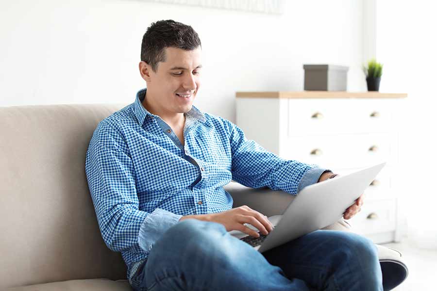 Hombre sentado en una sala utilizando su laptop