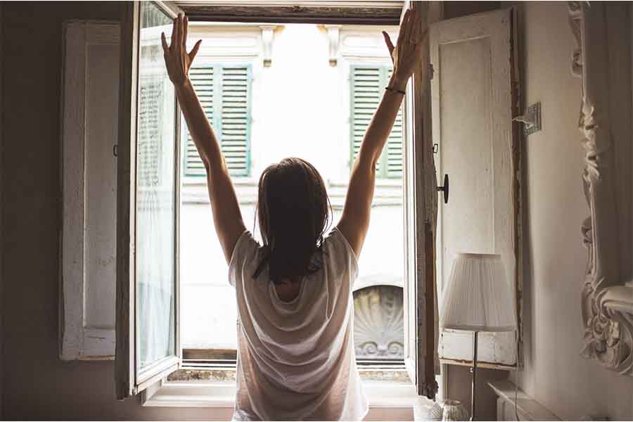 mujer con blusa blanca abriendo ventana