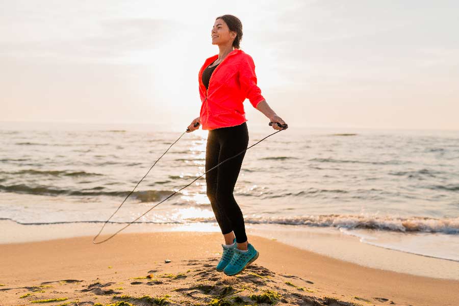 Mujer saltando la cuerda en el mar