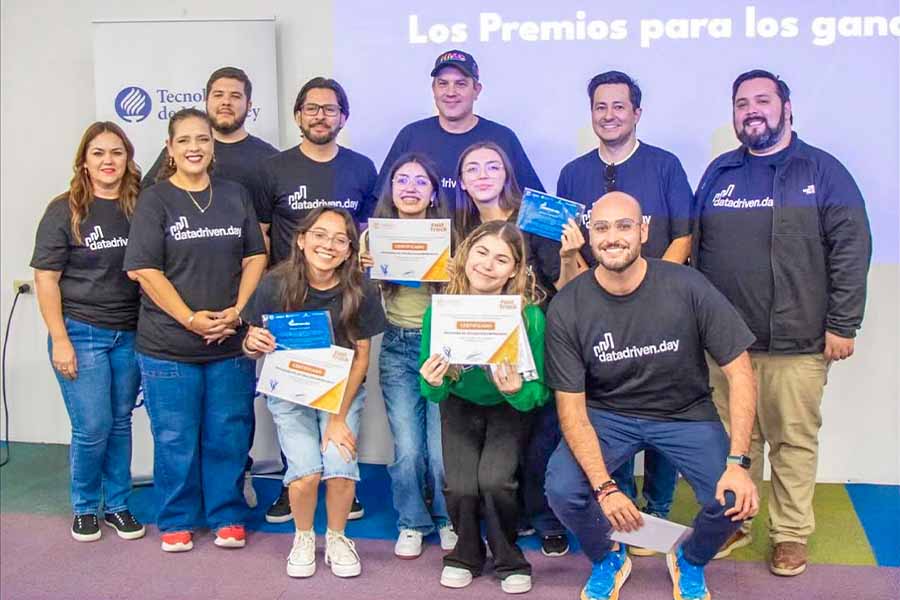 Un grupo de 12 personas posando juntas, al centro, cuatro chicas sostienen reconocimientos de ganadores. 