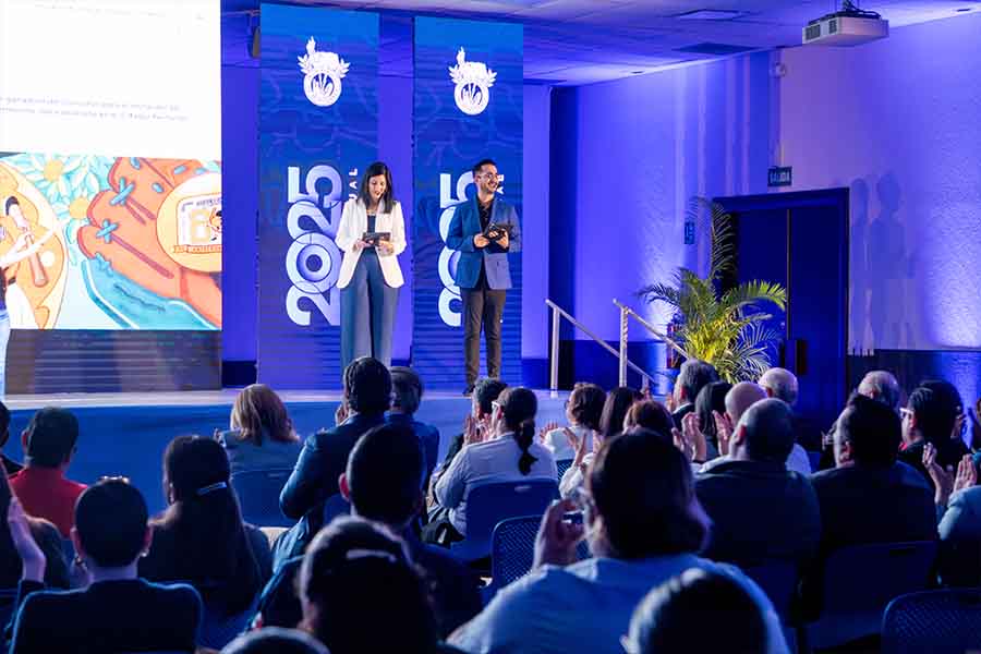 Una mujer y hombre sobre un escenario frente a un p&uacute;blico.