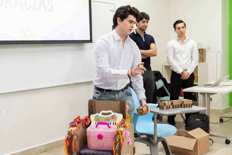 Estudiantes presentando su silla en clase y siendo evaluados