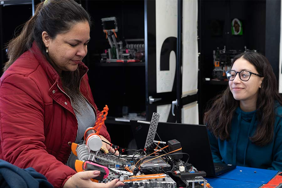 profesora y alumna analizando y armando un robot 