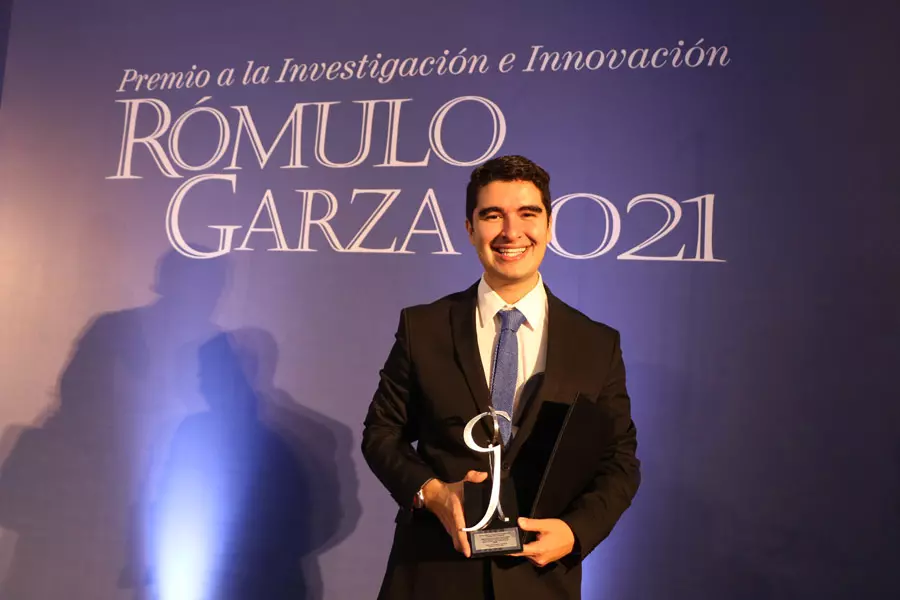 Rodrigo Ruz sosteniendo su Premio Rómulo Garza 2021.