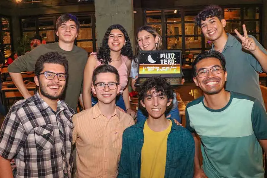 Grupo de estudiantes sosteniendo una laptop que muestra la pantalla de inicio de un videojuego de su propia autor&iacute;a. 