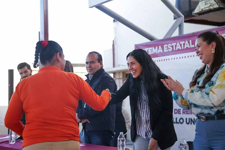 Una mujer interna del Cereso Femenil da la mano a directivos en ceremonia de graduación.