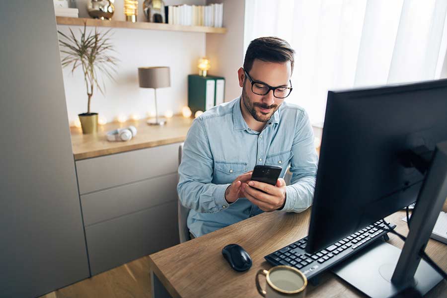 Hombre joven trabajando desde casa, haciendo una llamada por teléfono