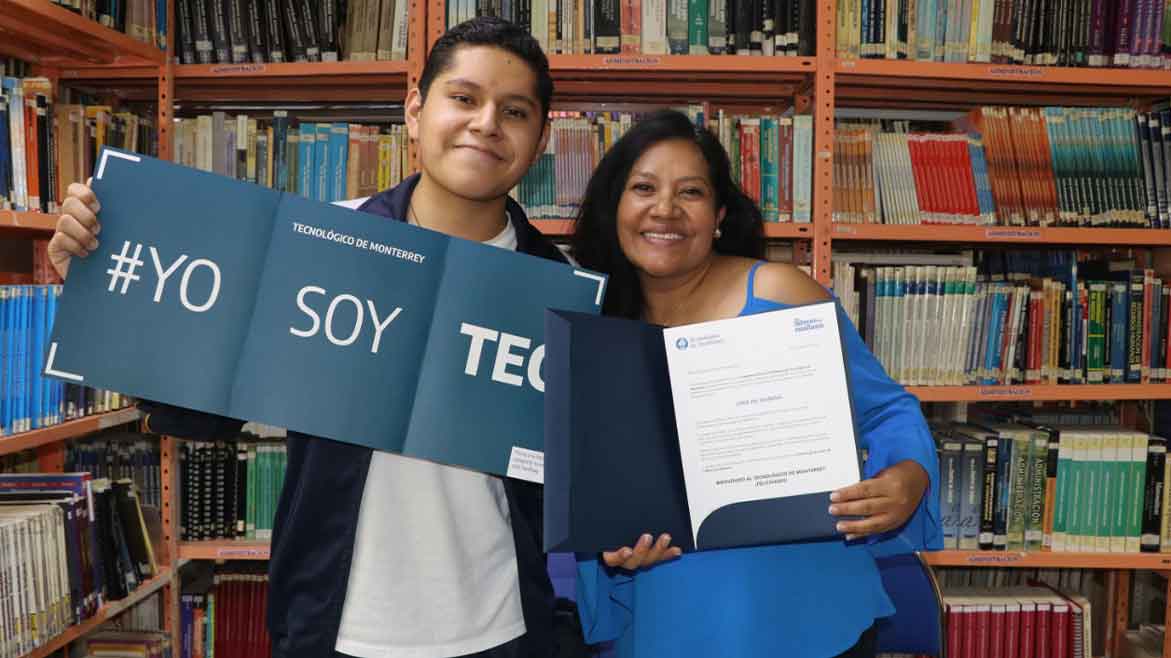 Estudiante de San Luis Potosí acepta la beca Líderes del Mañana y posa para foto junto a su mamá en biblioteca.