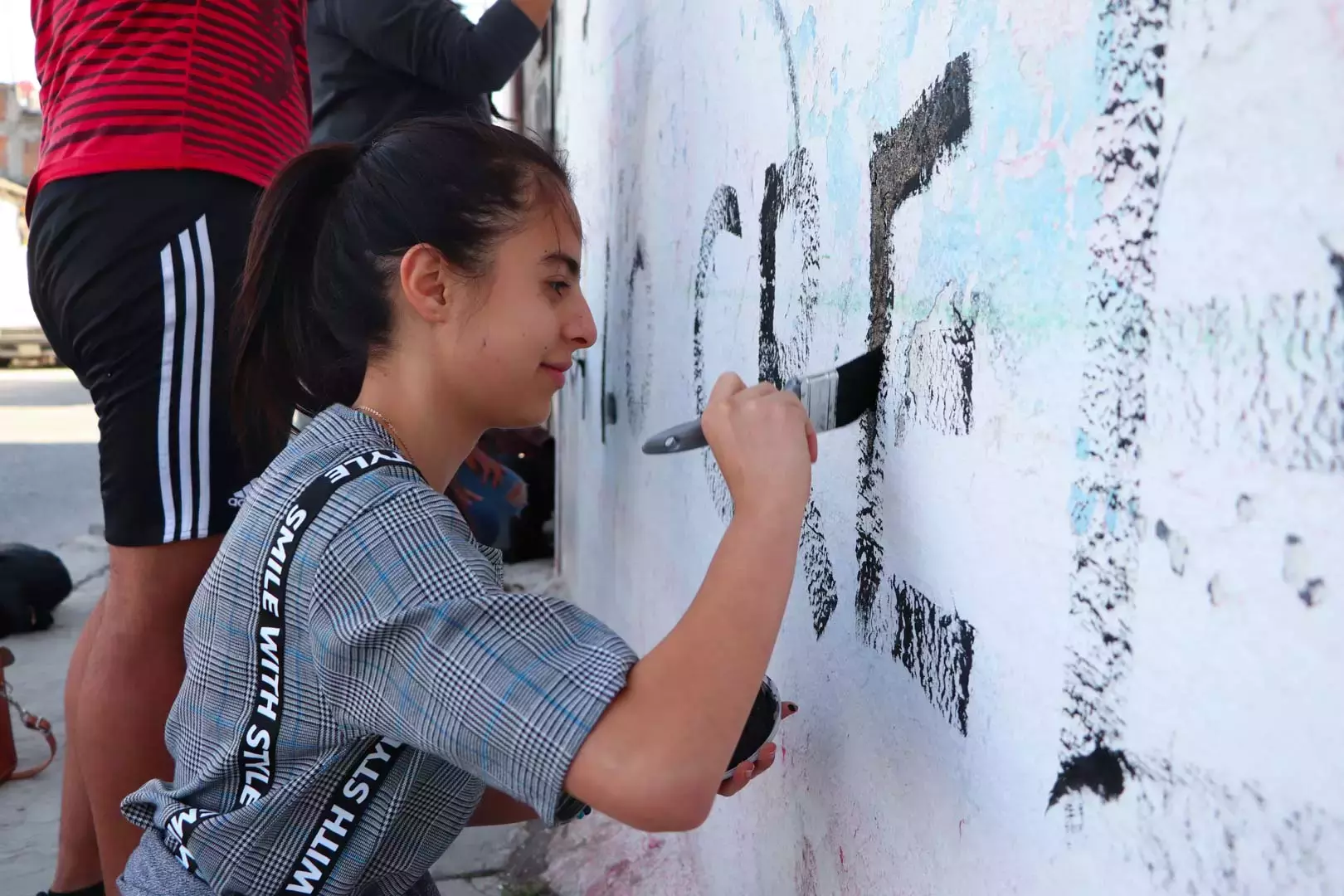 Alumnos y Armando Alanís pintando paredes con frases poéticas