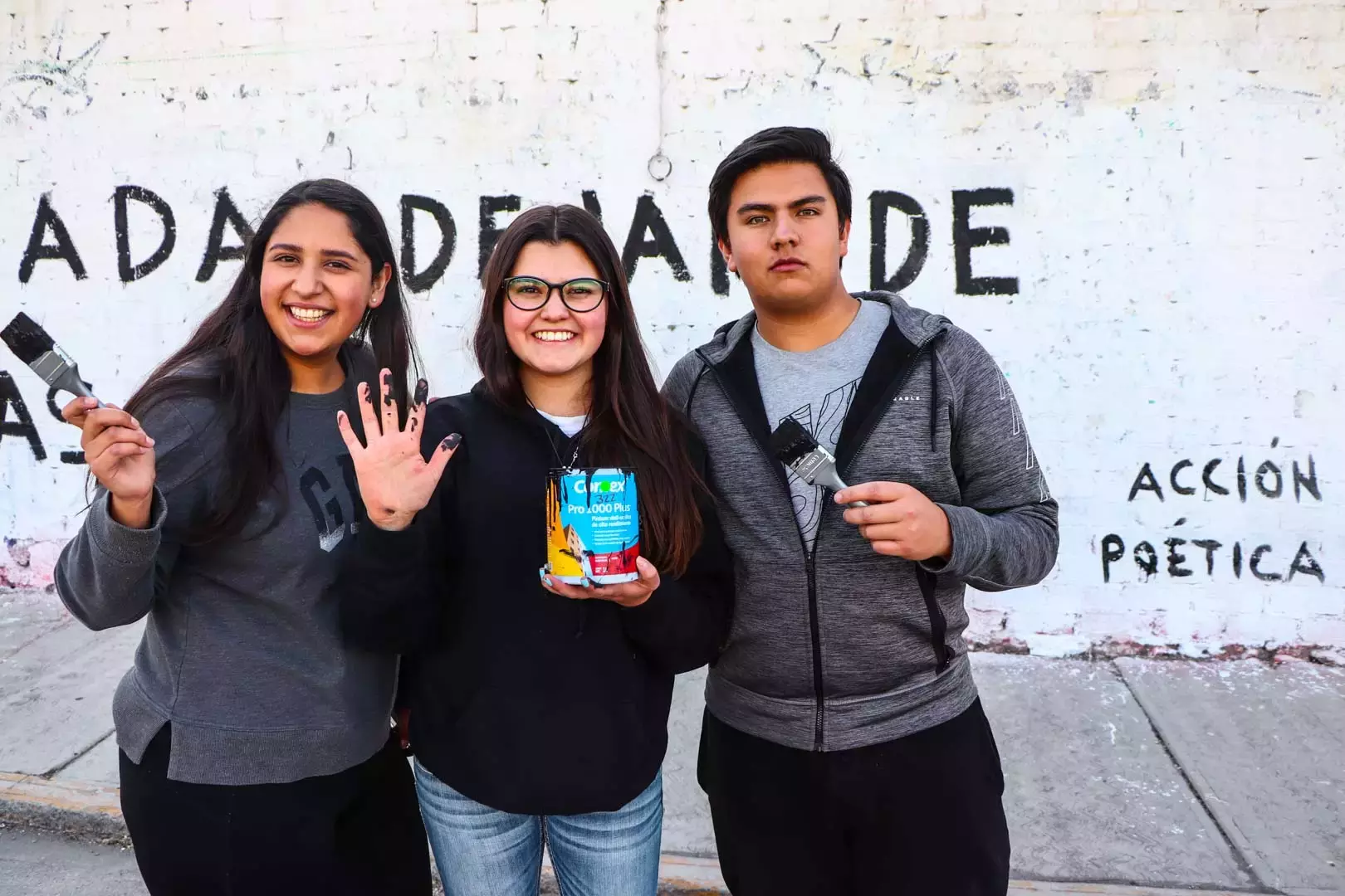 Alumnos y Armando Alanís pintando paredes con frases poéticas