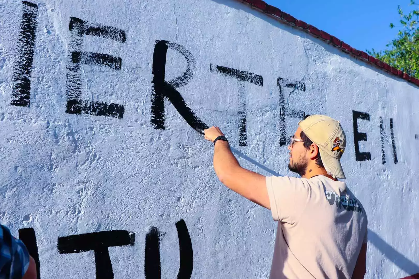 Alumnos y Armando Alanís pintando paredes con frases poéticas