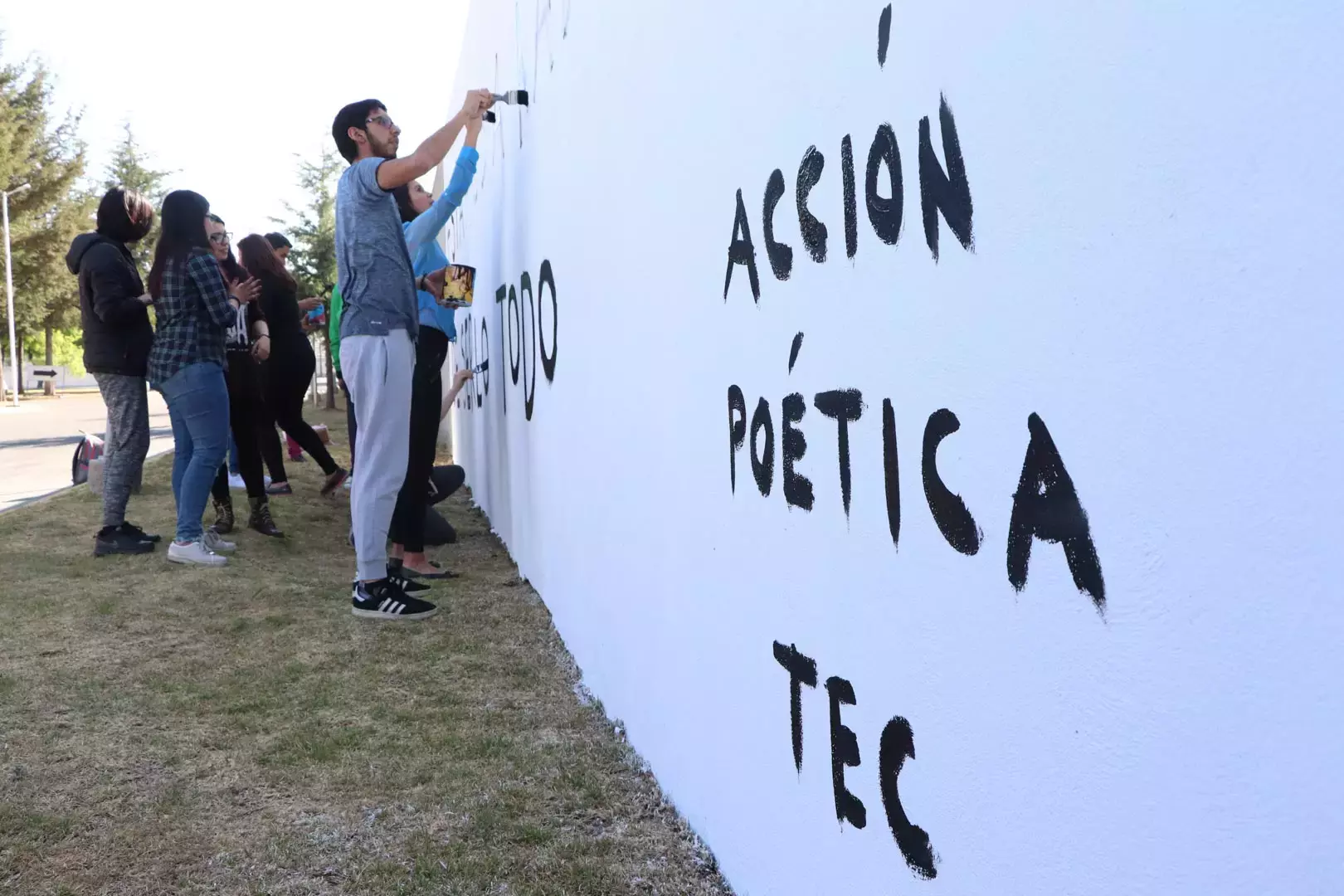 Alumnos y Armando Alanís pintando paredes con frases poéticas