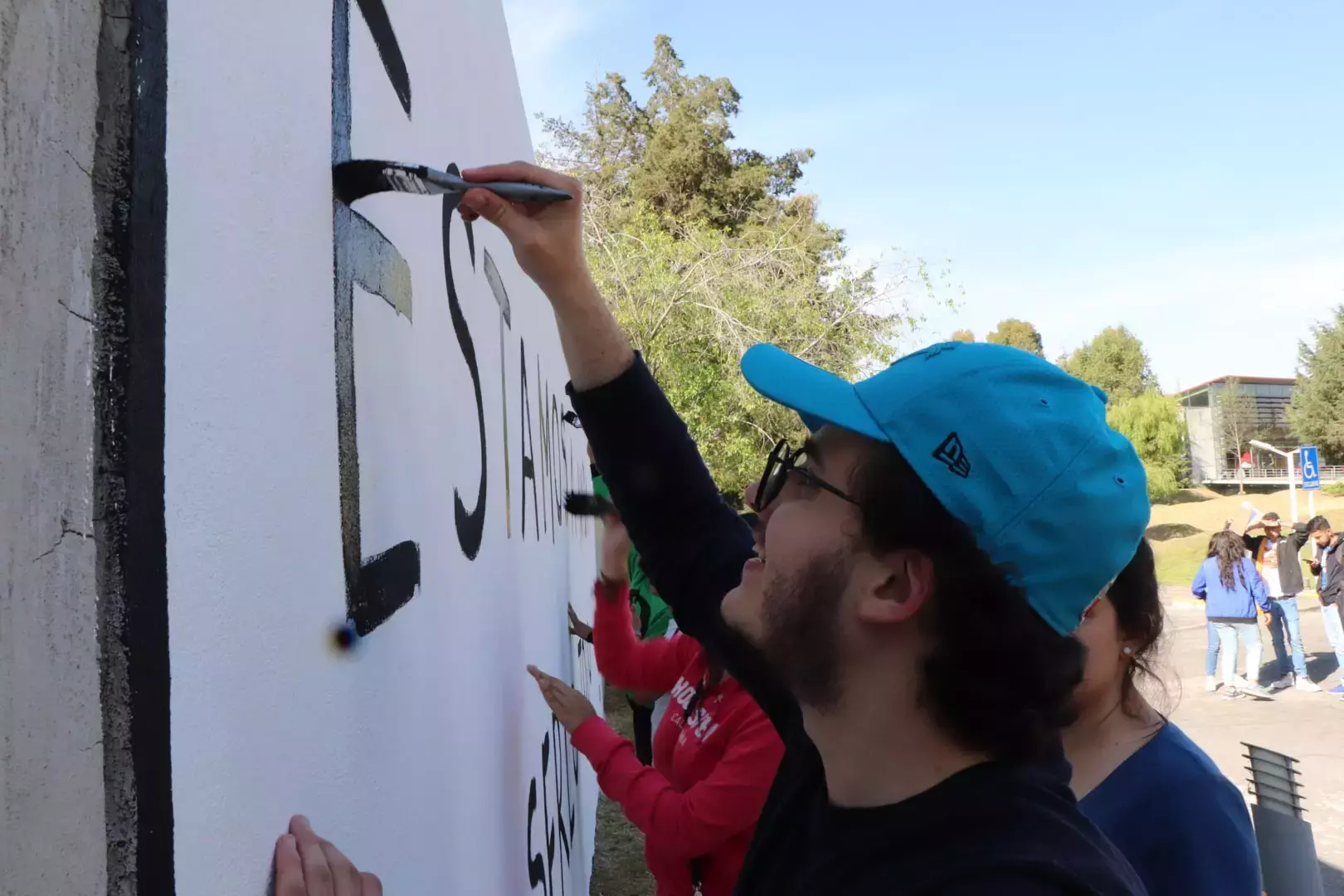 Alumnos y Armando Alanís pintando paredes con frases poéticas