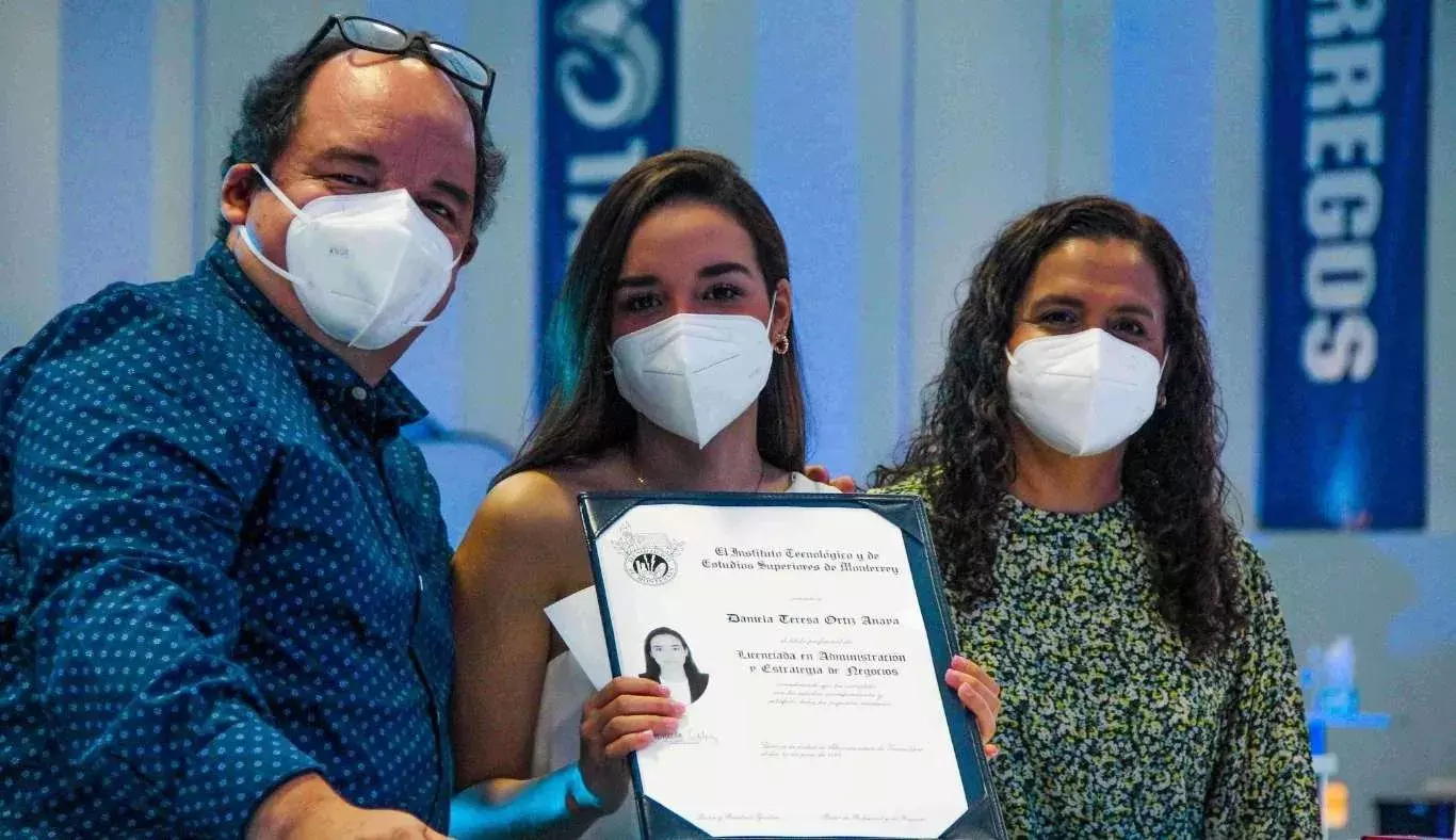 Foto familiar de alumna sosteniendo título universitario y sus padres a los lados.