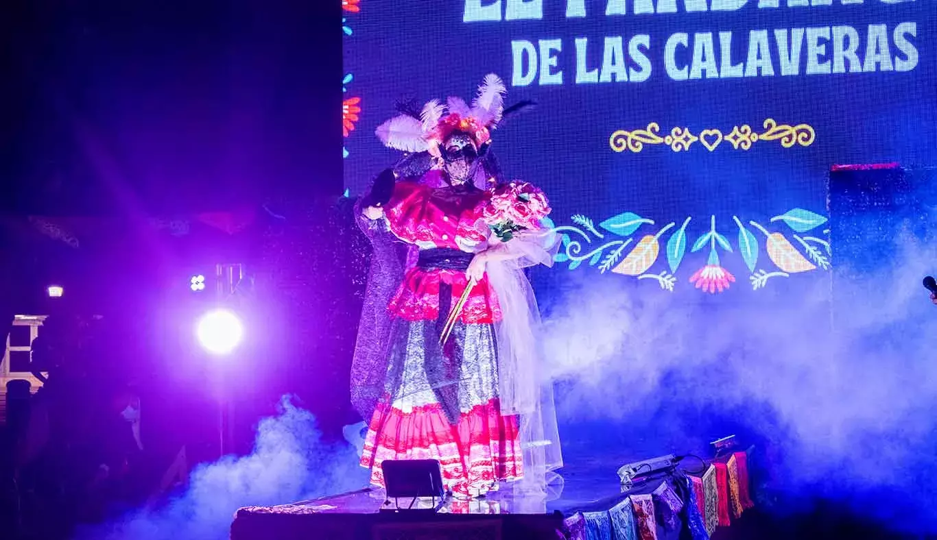 Una catrina con vestuario rosa desfila por la pasarela