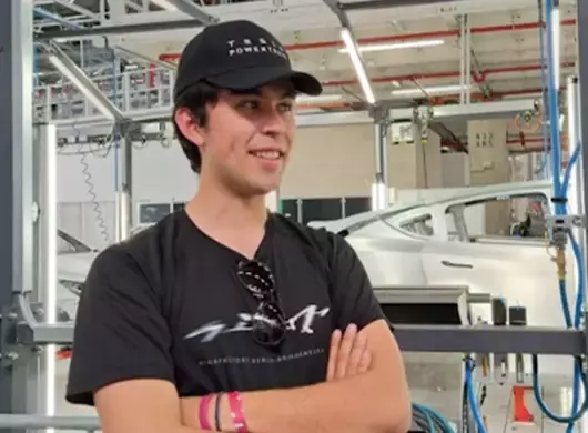 Estudiante posando para una foto en una planta automotriz