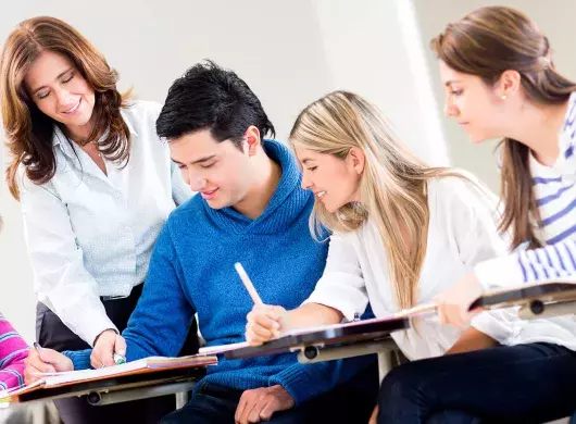 Profesora interactuando con un grupo de 4 alumnos