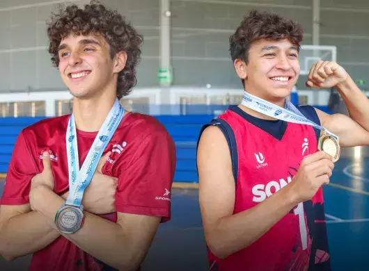 Dos jugadores de basquetbol posando con sus medallas del Nacional CONADEP en la Arena Borregos