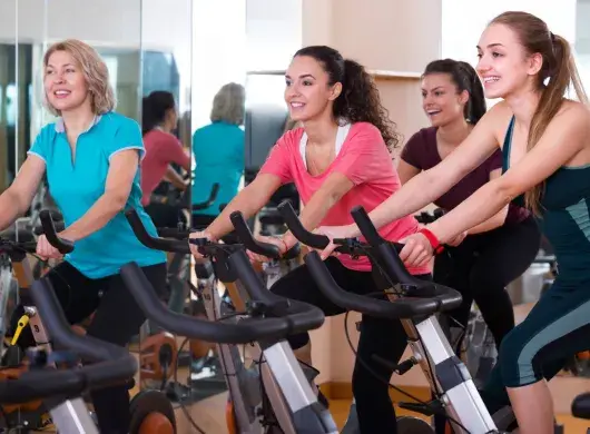 Mujeres de distintas edades realizando spinning en un gimnasio
