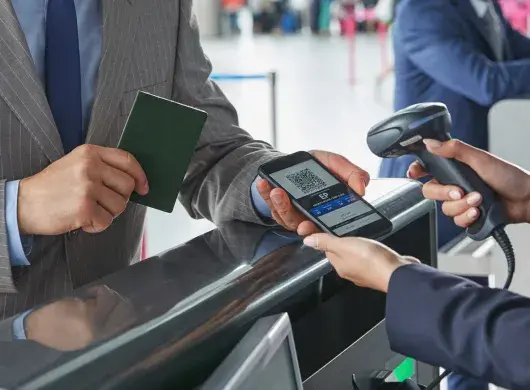 Representante de atención al cliente escaneando el código QR del pase de abordar en un teléfono inteligente en el mostrador de check-in del aeropuerto.