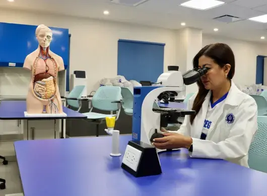 Karla Rojas observa una muestra a través de un microscopio en un laboratorio académico.