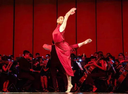 Bailarina en rojo del Tec de Monterrey campus Laguna realiza su movimiento dancístico con la Orquesta filarmónica DIME de fondo en el Teatro Nazas Torreón