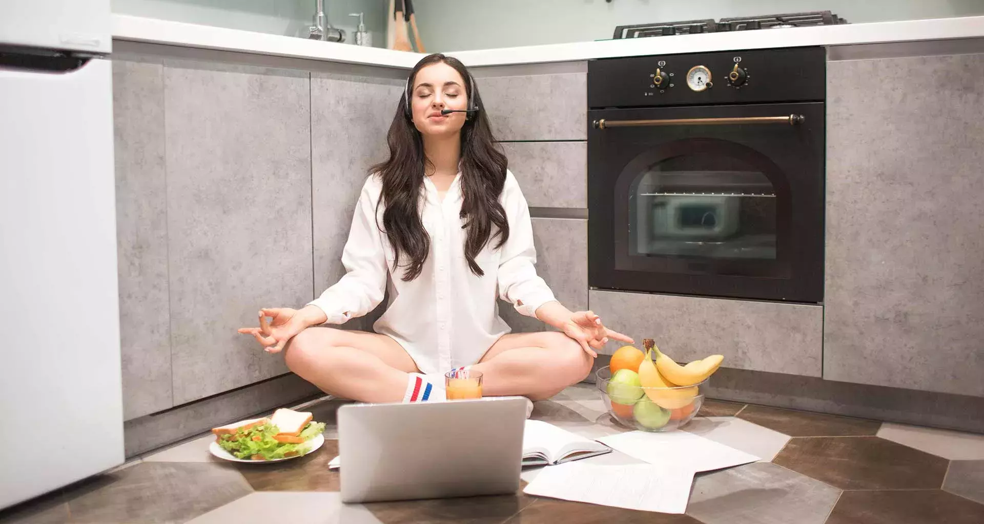 Joven con computadora, en posición de yoga y comida saludable alrededor, para representar el concepto de una rutina equilibrada