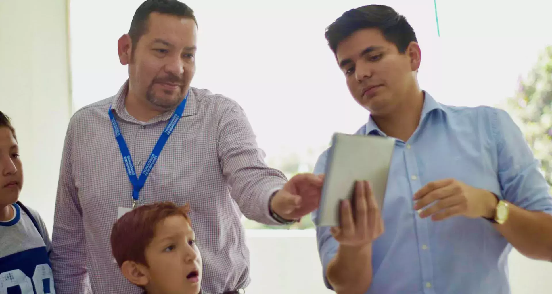 alumno del Tec presentando su proyecto de ingeniería a niños y a un profesor.